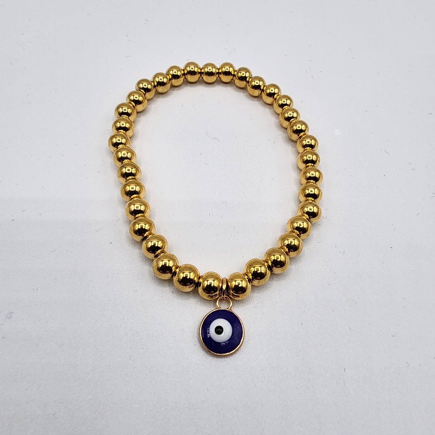 Nylon bracelet with 6 mm golden stainless steel beads and blue evil eye charm