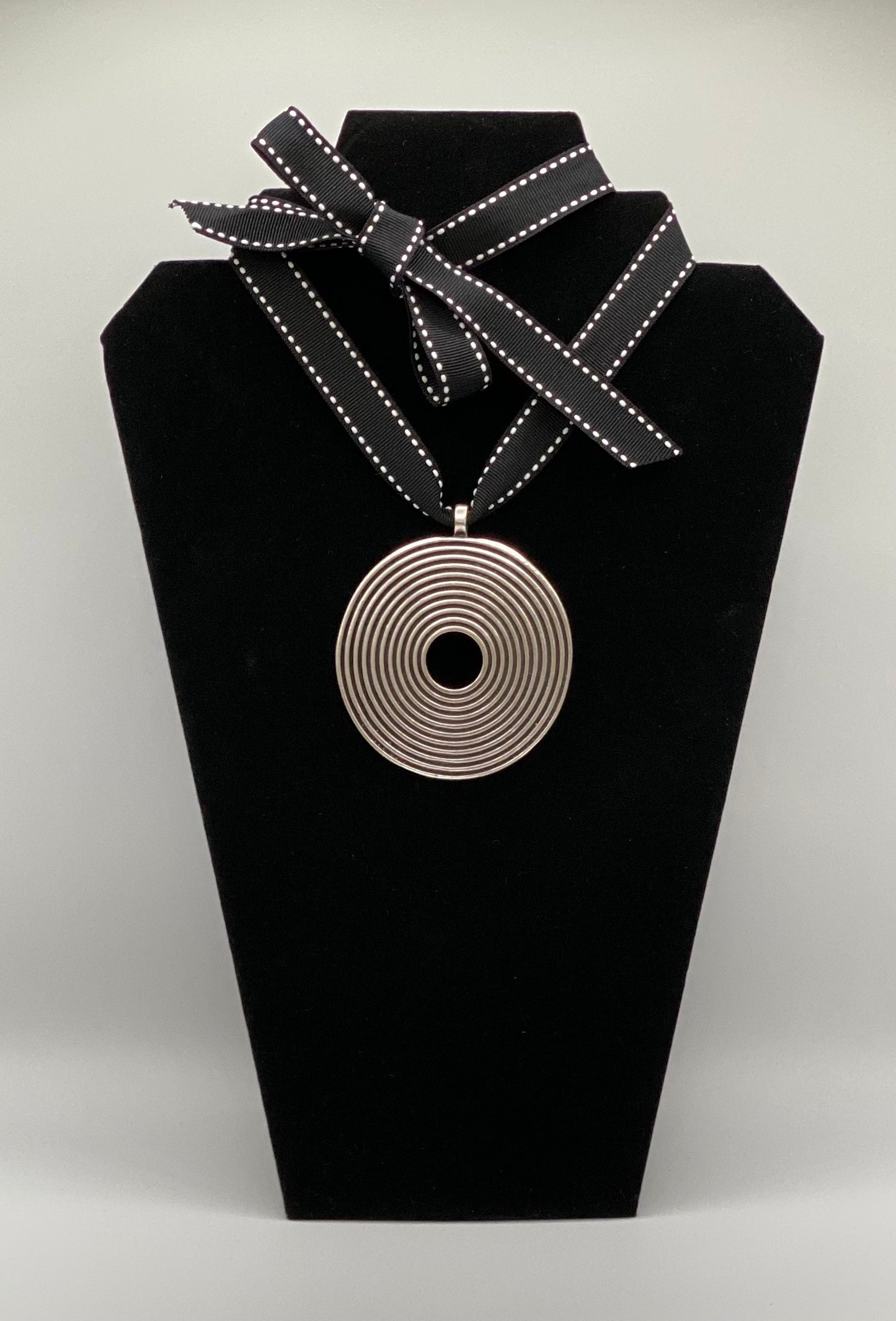 Black and white ribbon with silver plated spiral medallion